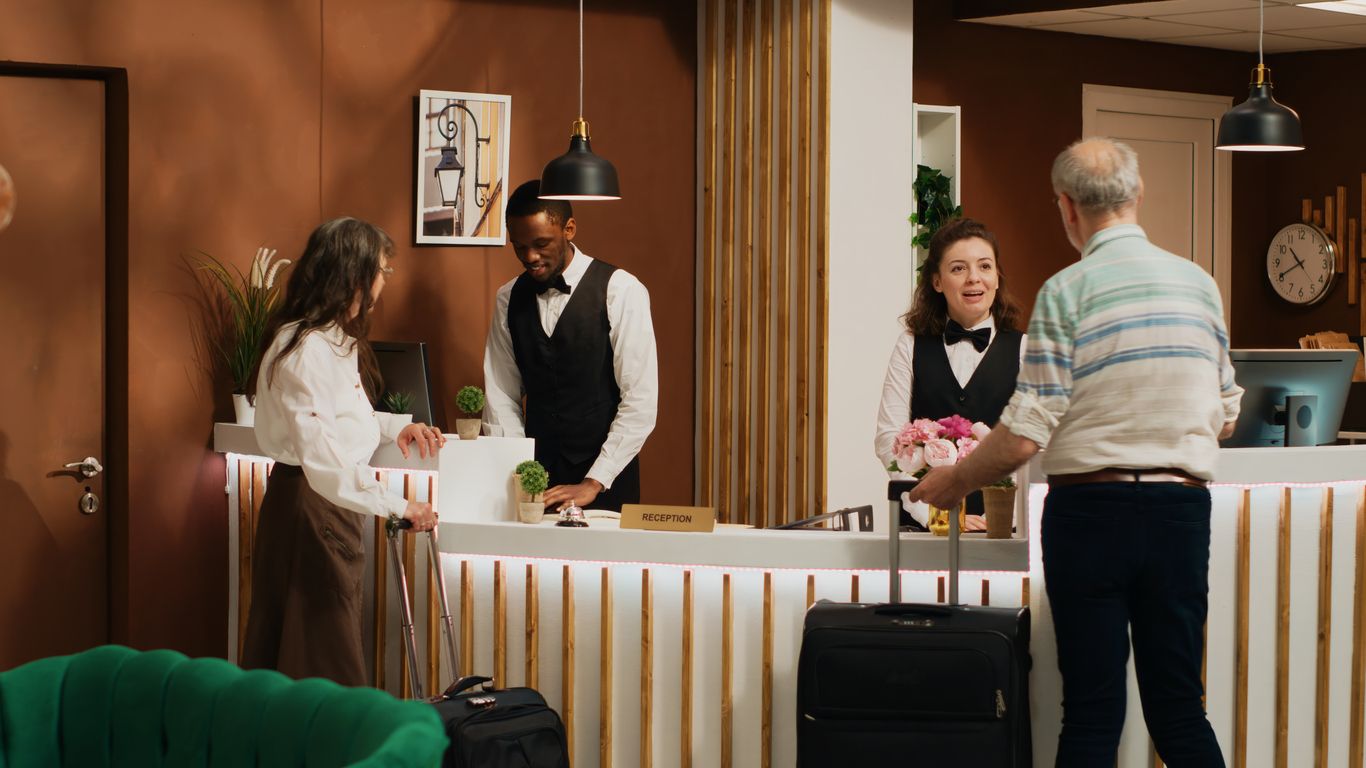 Hotel guests checking in at a front desk in the 1980s, showcasing vintage hospitality style and service.