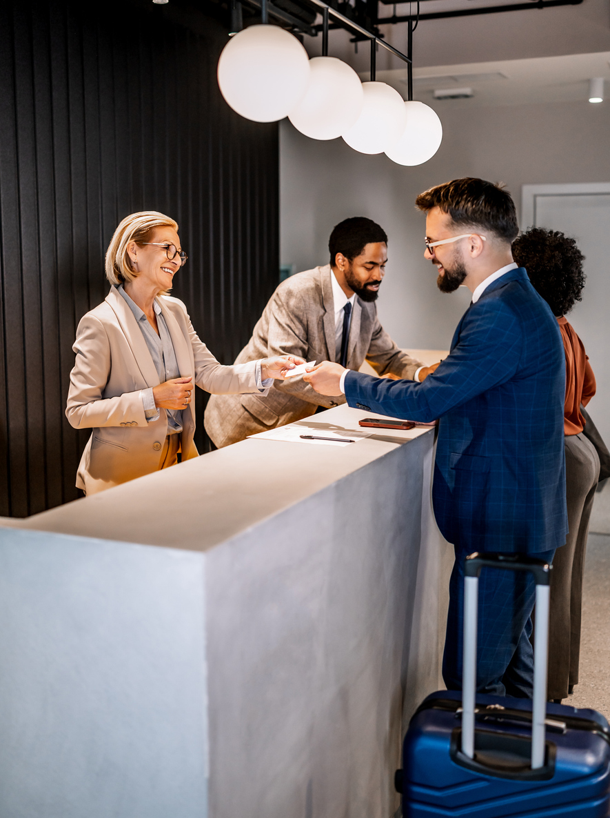 Hotel front desk associate warmly welcoming guests during check-in, creating a memorable hotel stay through exceptional hospitality and personalized service.